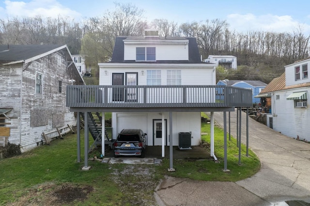 back of property featuring a lawn, central AC unit, an attached garage, and a wooden deck