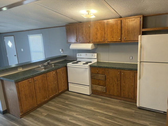 kitchen featuring a peninsula, white appliances, dark countertops, a sink, and extractor fan