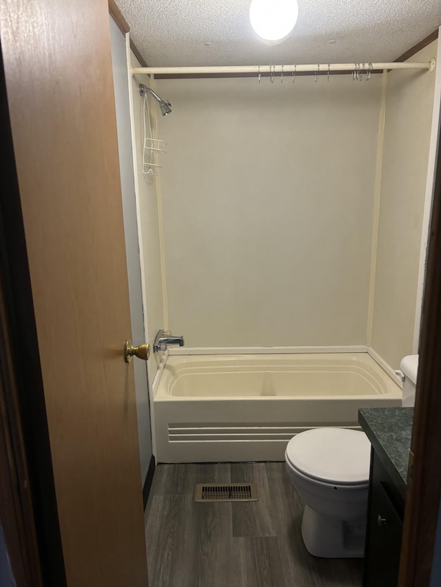 full bathroom with toilet, vanity, shower / bathtub combination, wood finished floors, and a textured ceiling