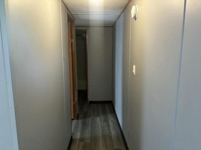 corridor with baseboards, a textured ceiling, and wood finished floors