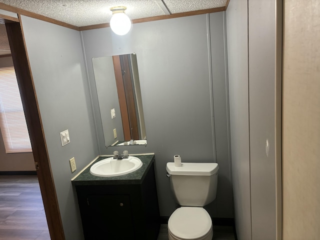 bathroom with toilet, vanity, wood finished floors, a textured ceiling, and baseboards