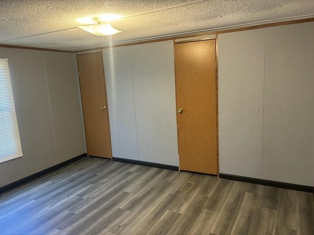unfurnished bedroom featuring a textured ceiling, a closet, and wood finished floors