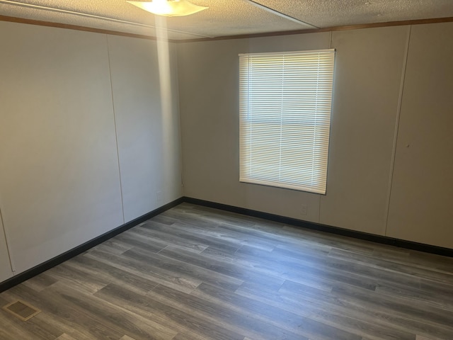 spare room with dark wood-type flooring, a textured ceiling, and visible vents