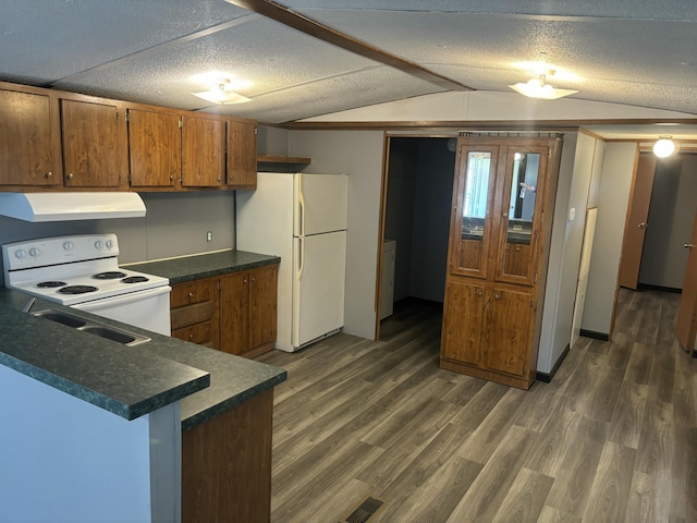 kitchen with brown cabinets, lofted ceiling, under cabinet range hood, white appliances, and dark countertops