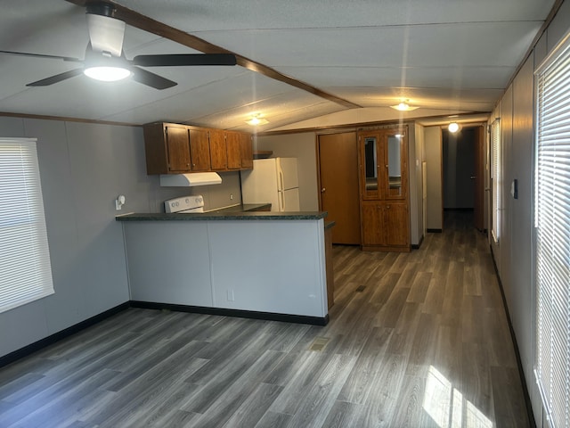 kitchen with vaulted ceiling, freestanding refrigerator, a peninsula, brown cabinetry, and dark countertops