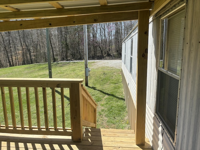 deck featuring a lawn and a view of trees