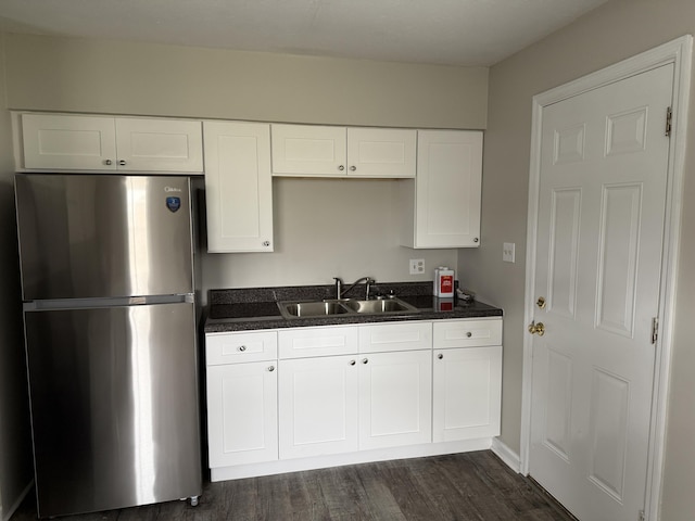 kitchen with dark wood-type flooring, white cabinetry, a sink, and freestanding refrigerator