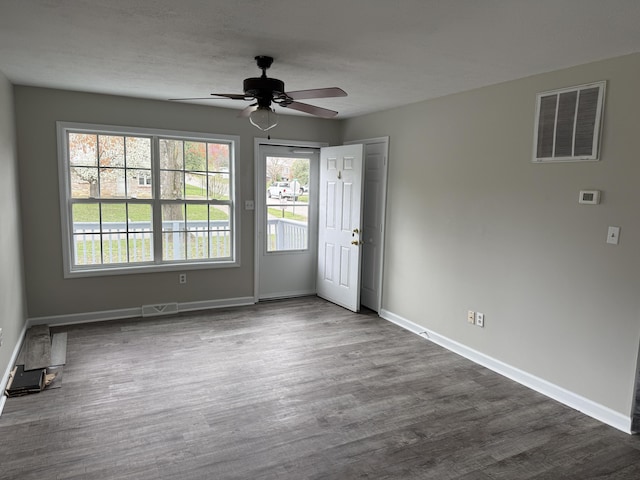 empty room featuring baseboards, dark wood-style flooring, ceiling fan, and visible vents
