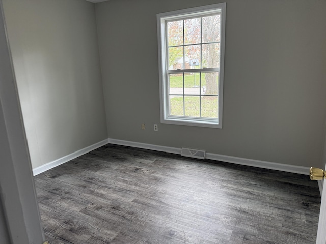 empty room featuring baseboards, visible vents, and dark wood finished floors