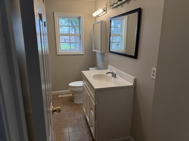 half bath featuring tile patterned flooring, vanity, toilet, baseboards, and visible vents