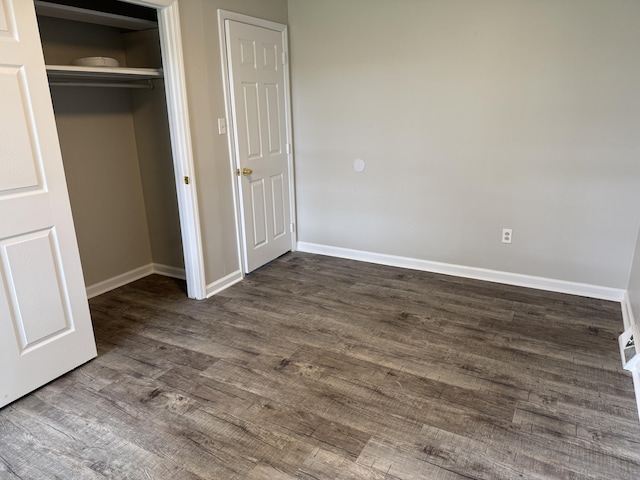 unfurnished bedroom featuring baseboards, visible vents, a closet, and dark wood-type flooring