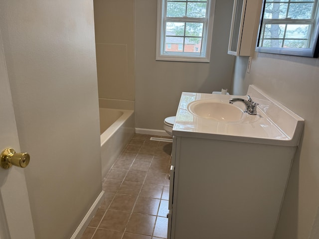 bathroom featuring baseboards, toilet, tile patterned floors, vanity, and a tub to relax in