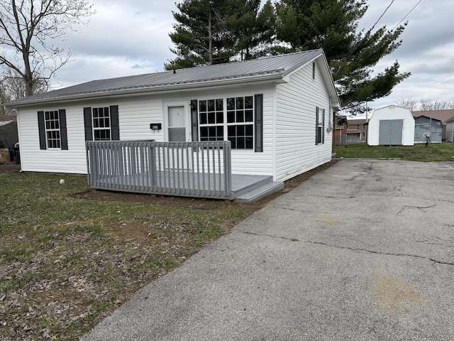 view of front of home featuring aphalt driveway, a deck, and metal roof