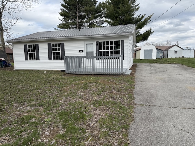 view of front facade with driveway, a front lawn, and metal roof
