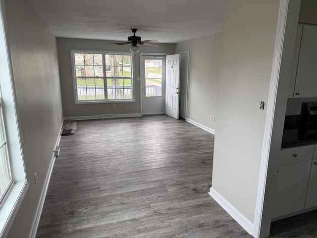 spare room with baseboards, dark wood-style flooring, and a ceiling fan