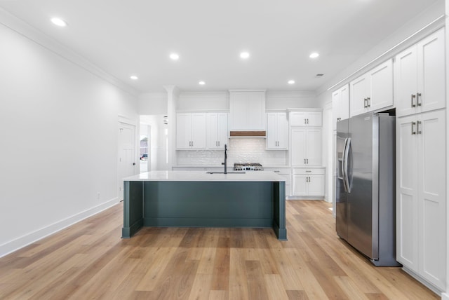 kitchen with stainless steel fridge with ice dispenser, white cabinets, a sink, ornamental molding, and custom range hood