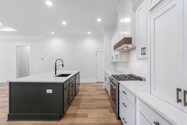kitchen with an island with sink, white cabinetry, backsplash, stainless steel appliances, and a sink