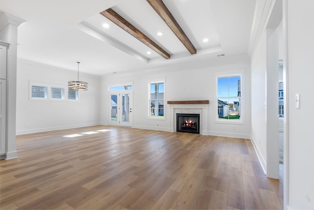 unfurnished living room featuring a chandelier, light wood-type flooring, baseboards, and a lit fireplace