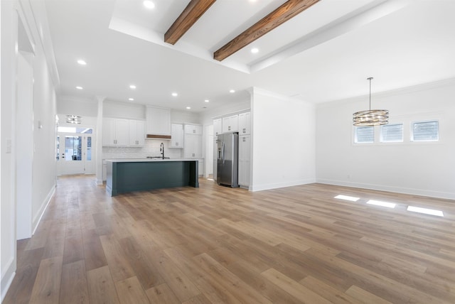 unfurnished living room with a sink, light wood finished floors, an inviting chandelier, and a healthy amount of sunlight