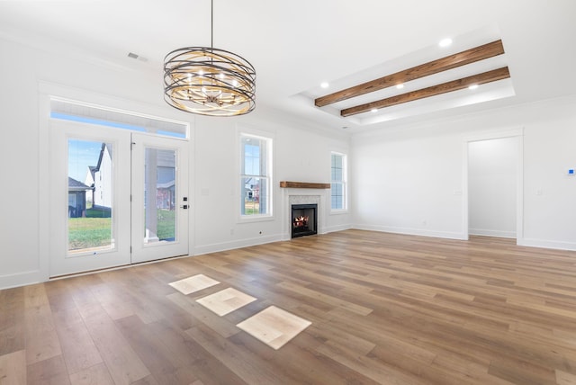 unfurnished living room with light wood-style floors, a lit fireplace, recessed lighting, a chandelier, and beam ceiling