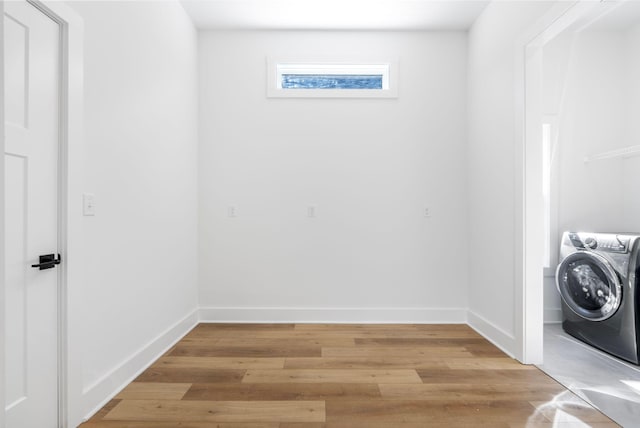 clothes washing area featuring light wood-style floors, baseboards, washer / dryer, and laundry area