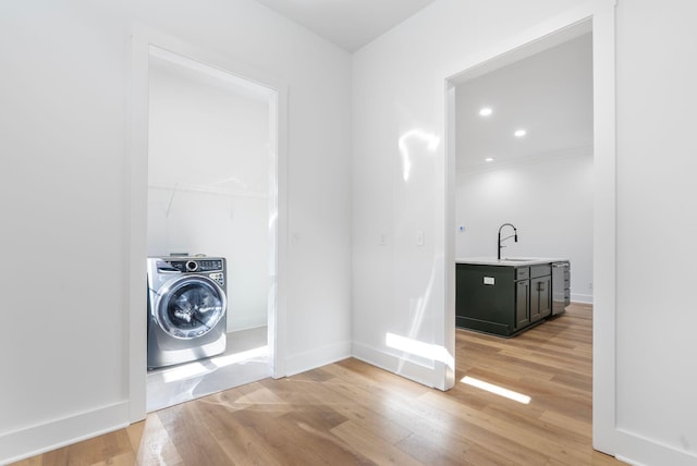 washroom featuring light wood-style flooring, laundry area, baseboards, and washer / dryer