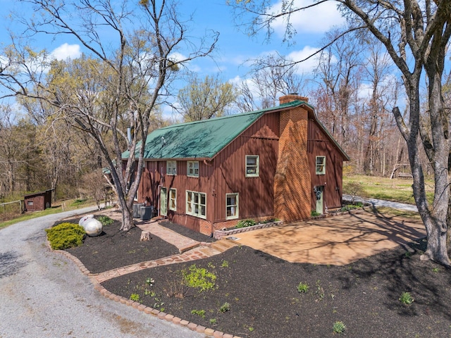 1295 Burger Knob Rd, Junction City, KY 40440 - view of front facade featuring central AC unit, a chimney, gravel driveway, and metal roof
