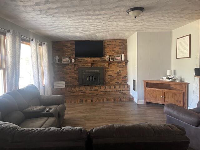 living room featuring visible vents, a textured ceiling, wood finished floors, and a brick fireplace