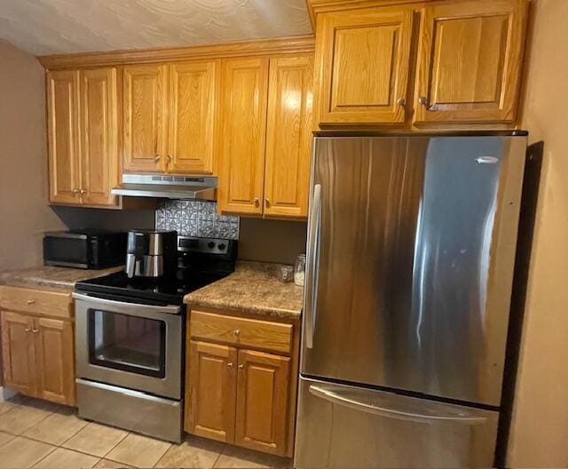 kitchen featuring light countertops, tasteful backsplash, under cabinet range hood, light tile patterned floors, and stainless steel appliances
