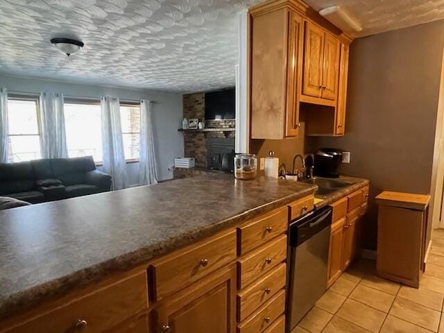 kitchen featuring light tile patterned flooring, a sink, a textured ceiling, stainless steel dishwasher, and brown cabinetry