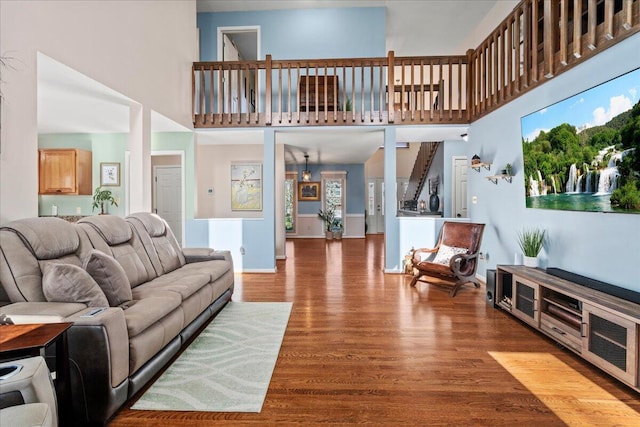 living area featuring a wealth of natural light, a towering ceiling, baseboards, and wood finished floors