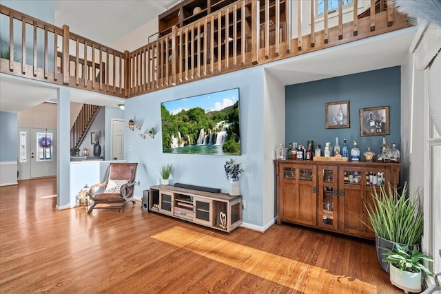 living area with a towering ceiling, baseboards, and wood finished floors