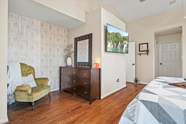 bedroom with an accent wall, baseboards, vaulted ceiling, and wood finished floors