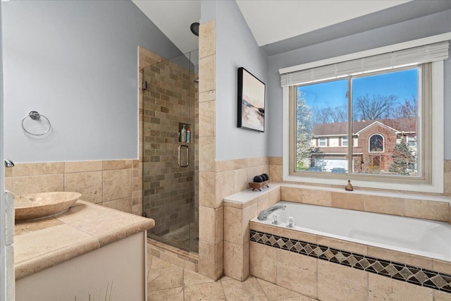 bathroom with a bath, lofted ceiling, tile walls, a stall shower, and tile patterned floors