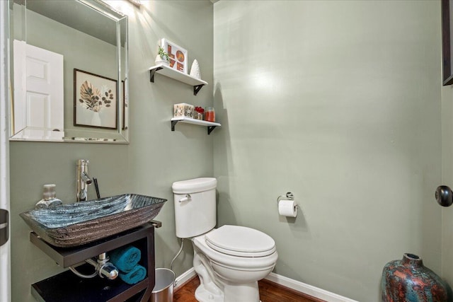 bathroom featuring toilet, wood finished floors, a sink, and baseboards