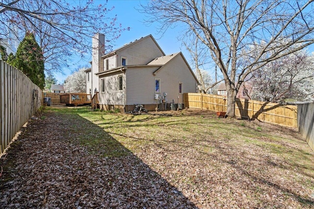 back of house with a yard, a fenced backyard, and a chimney