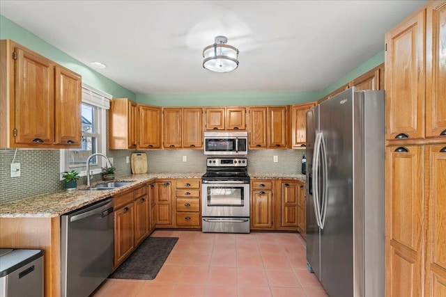 kitchen with light stone counters, light tile patterned floors, backsplash, stainless steel appliances, and a sink