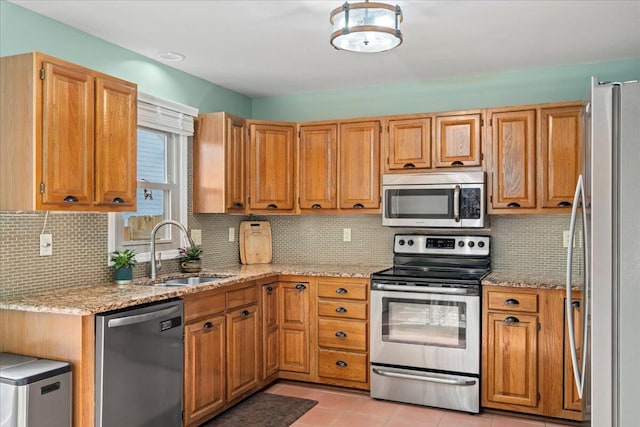 kitchen featuring tasteful backsplash, a sink, light stone counters, and appliances with stainless steel finishes