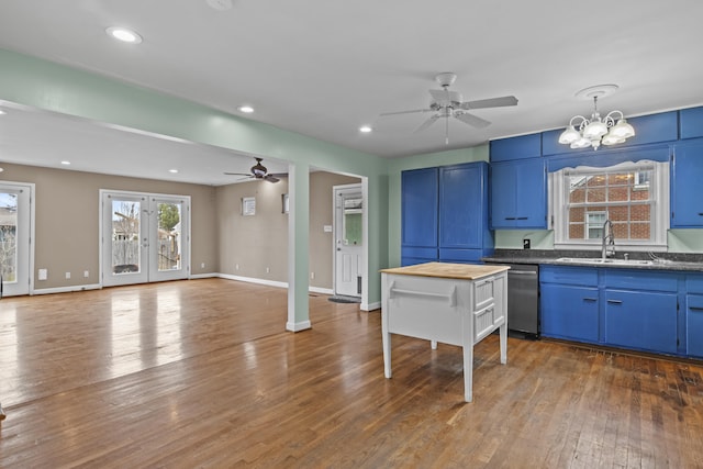 kitchen featuring blue cabinetry, a sink, ceiling fan with notable chandelier, and wood-type flooring