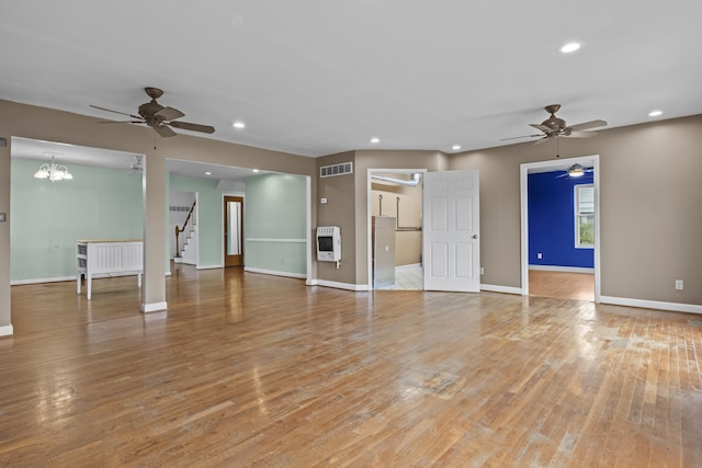 unfurnished living room featuring heating unit, visible vents, a ceiling fan, and light wood finished floors