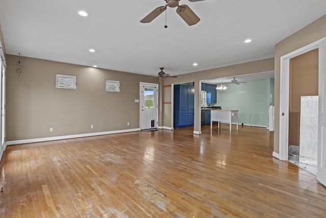 unfurnished living room with light wood finished floors, ceiling fan with notable chandelier, and recessed lighting