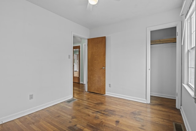 unfurnished bedroom featuring hardwood / wood-style floors, a closet, baseboards, and visible vents