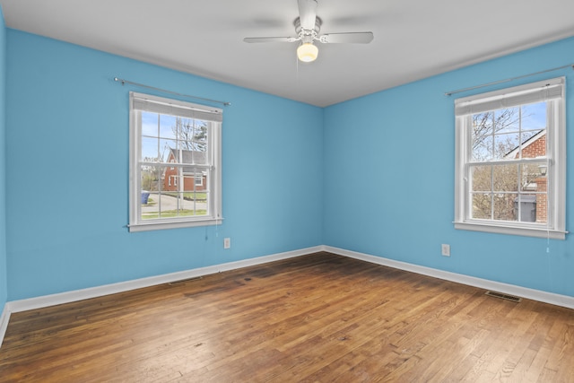 spare room with hardwood / wood-style floors, visible vents, and a healthy amount of sunlight