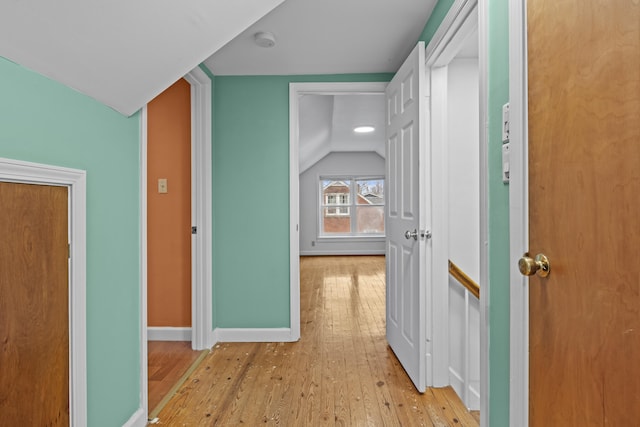 hall with baseboards, lofted ceiling, and wood-type flooring