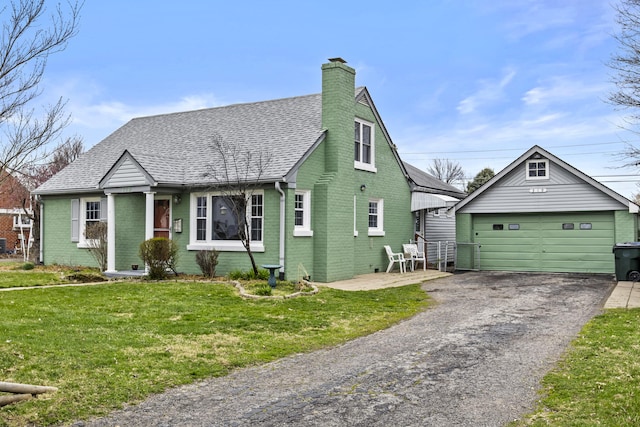 bungalow-style house featuring brick siding, a shingled roof, a front lawn, and an outdoor structure