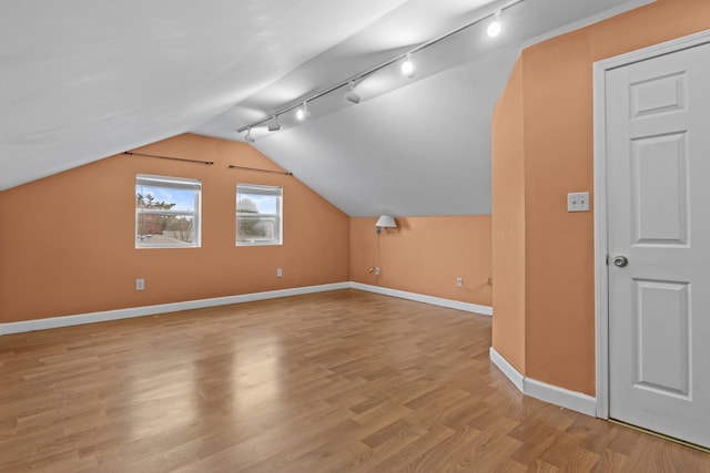 additional living space with light wood-style flooring, baseboards, and vaulted ceiling