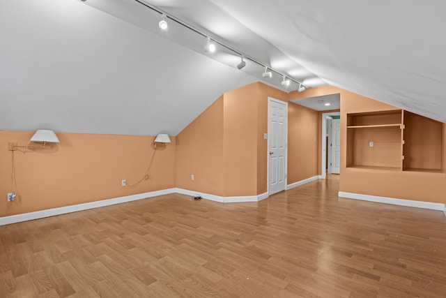 bonus room featuring baseboards, lofted ceiling, and light wood-style flooring