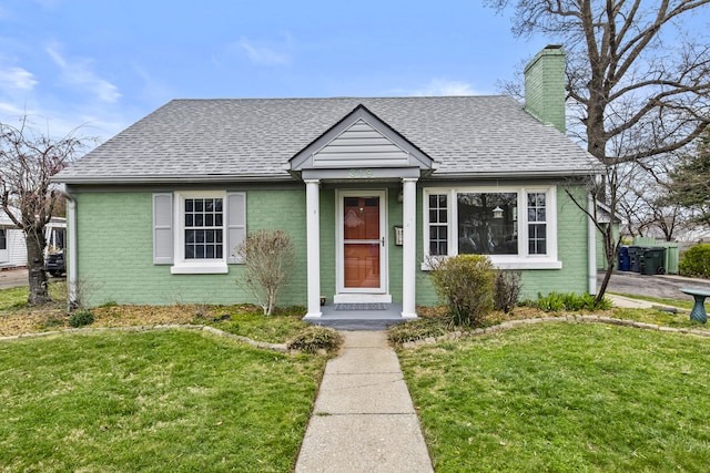 bungalow-style home featuring a chimney, a shingled roof, and brick siding