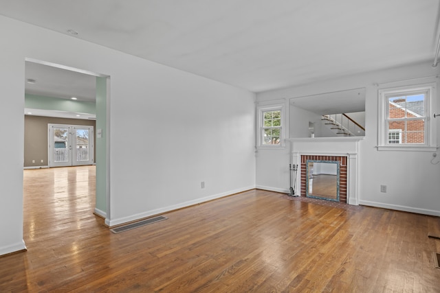 unfurnished living room with hardwood / wood-style floors, baseboards, a fireplace, and visible vents