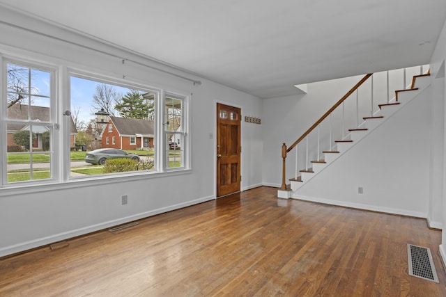 interior space with a wealth of natural light, visible vents, stairway, and wood-type flooring